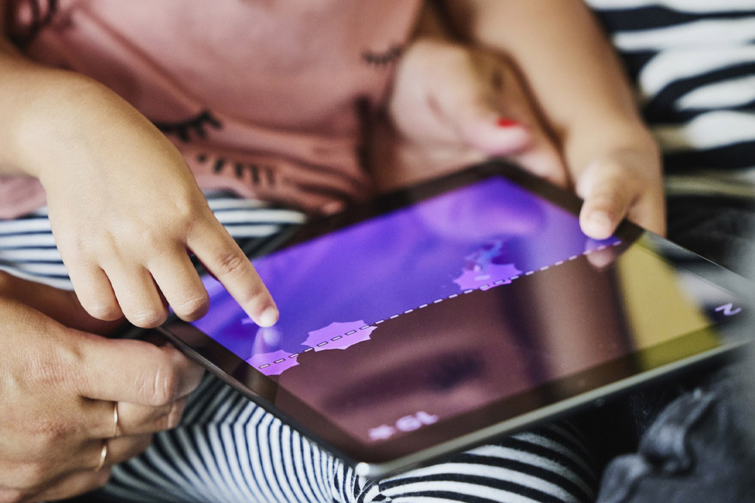 کودک درحال بازی با تبلت به کمک بزرگتر